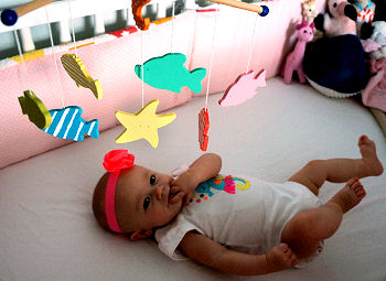 Evelyn in her crib enjoying a colorful tropical fish and seashell baby mobile