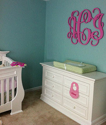Elegant pink teal and white baby girl nursery room with large painted wooden wall letters featuring a baby girl's initials in  a circular monogram