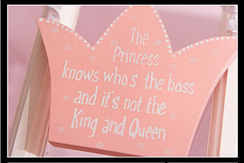 Pink and white painted, wooden princess crown saying The Princess Knows Who's the Boss and It's Not the King and Queen