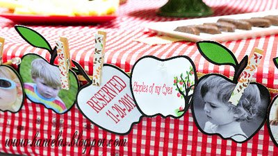 Apple of My Eye baby shower party banner with apple shaped photo cut outs with pictures of the kids draped on the dessert table