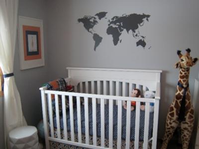 Baby boy gray and orange nursery with world map wall decorations.