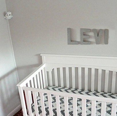 Corner shelf for a baby monitor in a neutral nursery.