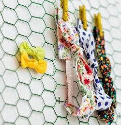 A DIY nursery wall letter made from painted chicken wire doubles as Willow's headband and bow holder